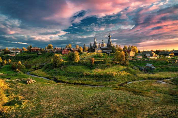 Village with churches and river at sunset