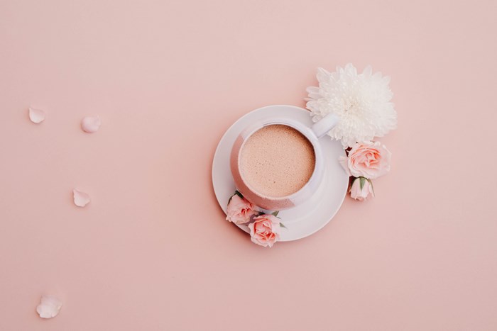 Pink coffee mug with flowers and petals on a pink background