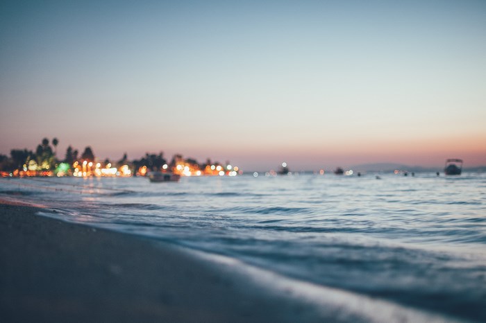 Beach at sunset with lights and boats