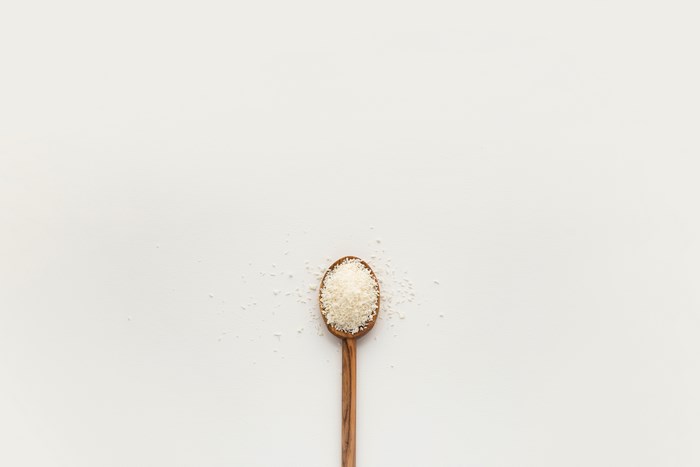 Wooden spoon filled with shredded coconut on a white background
