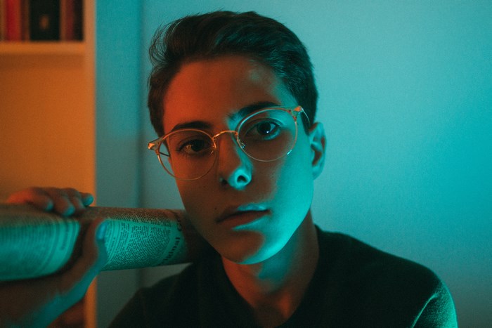 Person with glasses holding a newspaper