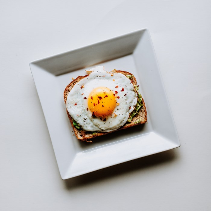 Avocado toast with fried egg on a white plate