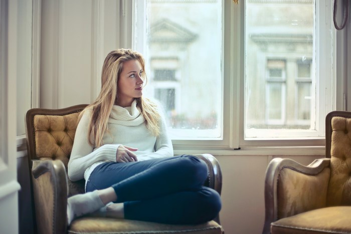Woman in white sweater sitting by the window