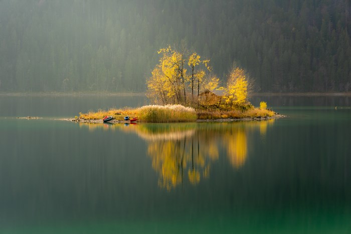 Island with autumn trees and kayaks on Eibsee lake in Bavaria