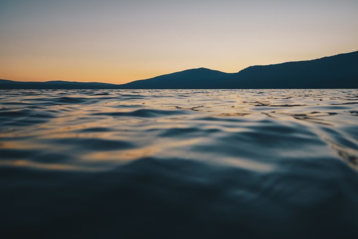 Sunset over a rippling lake with silhouetted mountains
