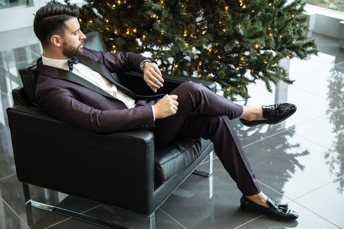 Man in Suit Sitting by Christmas Tree