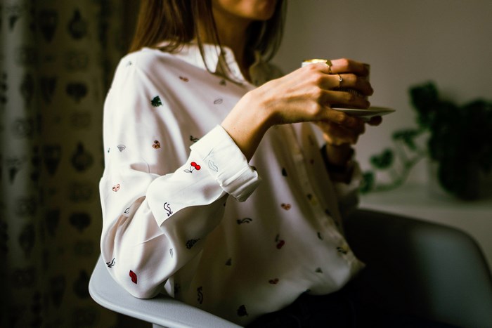 Woman in patterned blouse holding a cup
