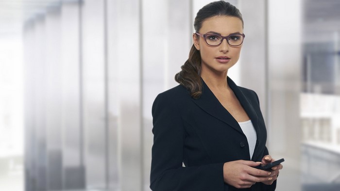 Woman in suit and glasses holding a phone