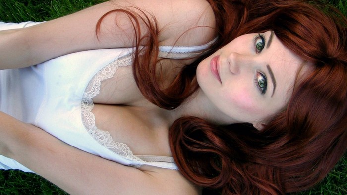 Woman with red hair lying on grass