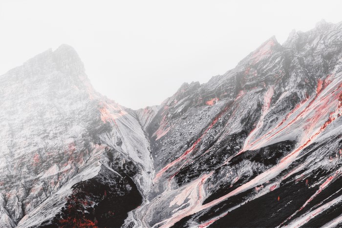Volcanic mountain range with red streaks under fog
