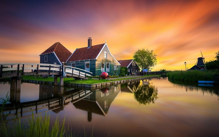 Dutch houses and windmill at sunset over canal