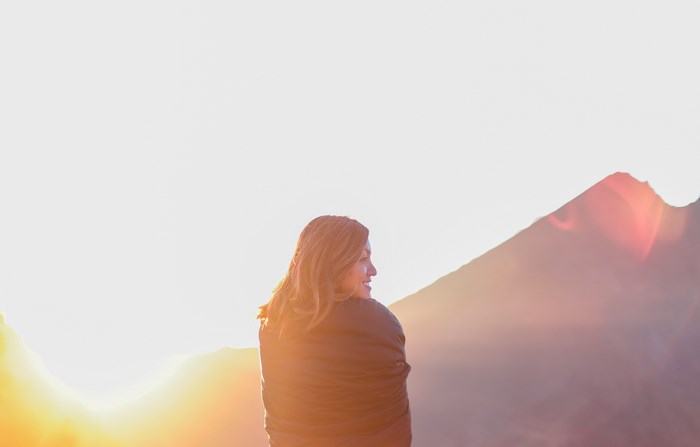 Woman wrapped in a blanket at sunrise with mountains
