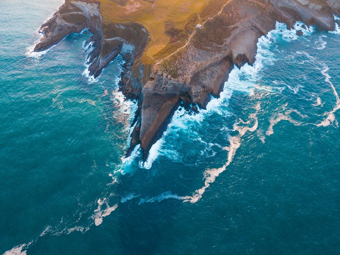 Aerial view of a rugged coastline with turquoise ocean waves