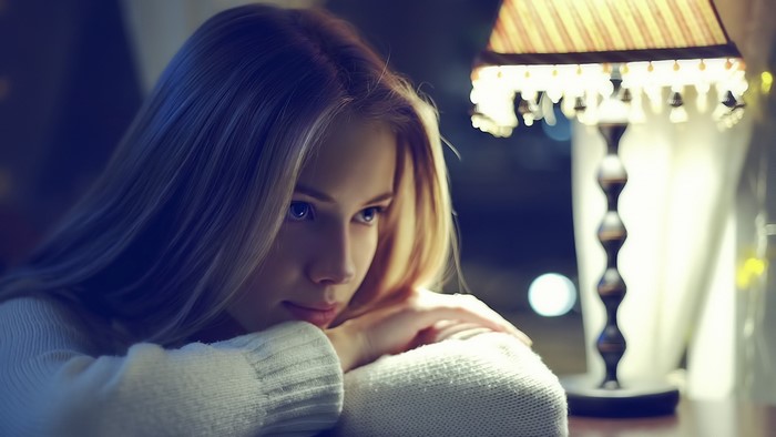 Young blonde woman looking away near a lamp