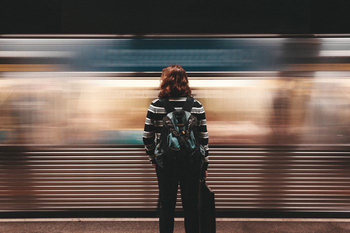 Person with backpack waiting for a train in motion