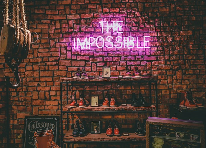 Neon sign "The Impossible" above boots display