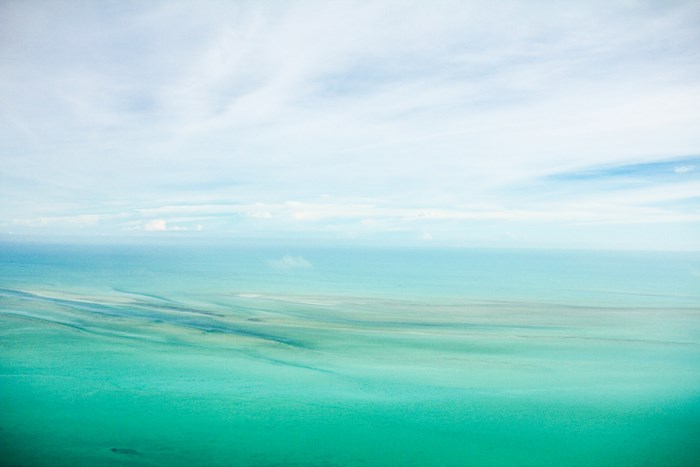 Turquoise ocean with sandbars under a cloudy sky