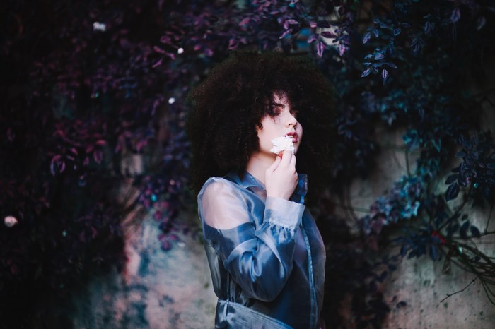 Woman with curly hair holding a white flower