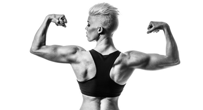 Muscular woman flexing biceps in monochrome
