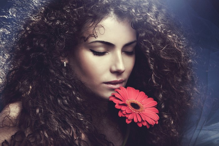 Woman with curly hair holding a red flower