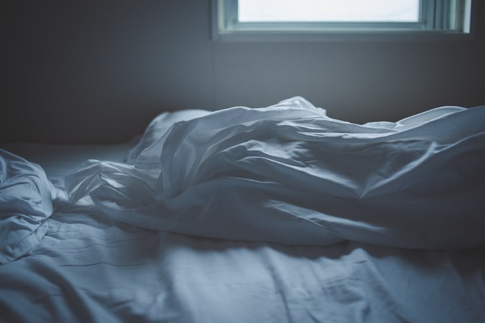 Empty rumpled bed with window light