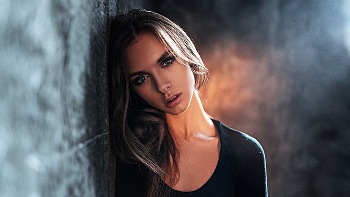 Woman with blue eyes leaning against a wall