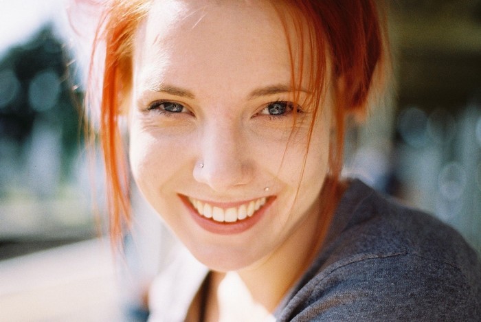 Woman with red hair and piercings smiling