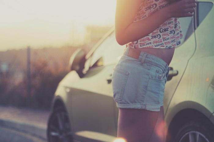 Woman in Coca-Cola top and jean shorts by car