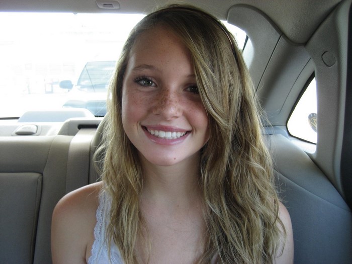 Young woman with freckles in a car's back seat