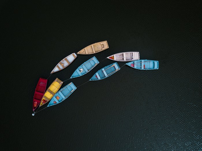 Aerial view of colorful rowboats tethered together on dark water