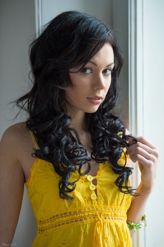 Woman with long black curly hair in yellow dress