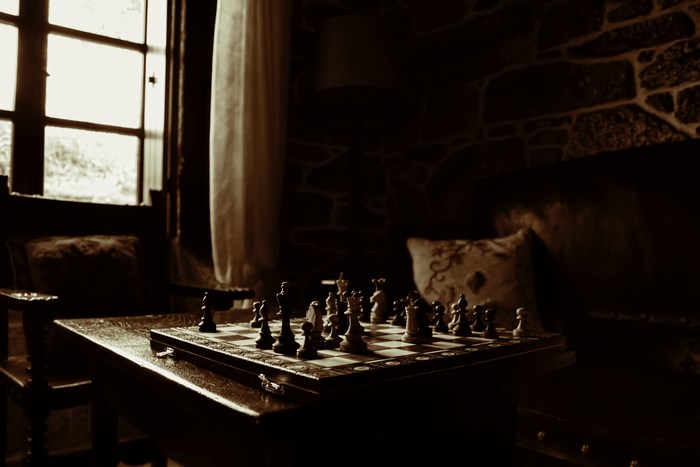 Dimly Lit Chess Game by Window with Cushions