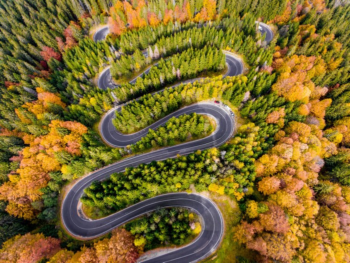 Aerial view of a winding road through an autumn forest