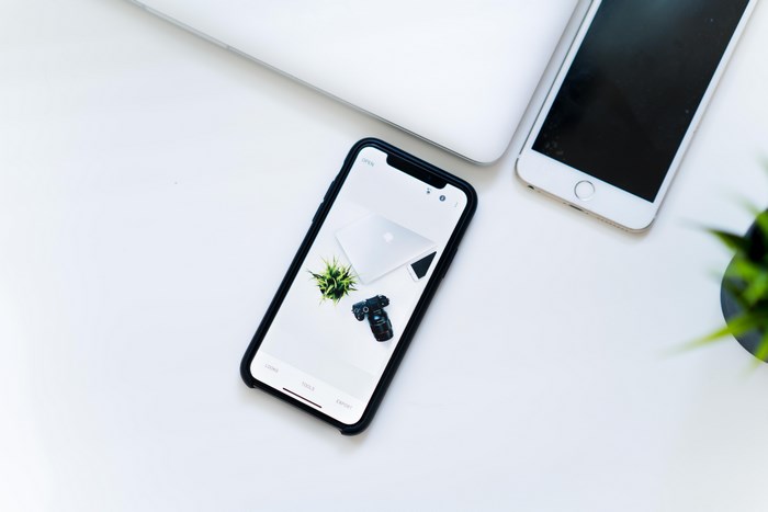 iPhone and MacBook on a white desk