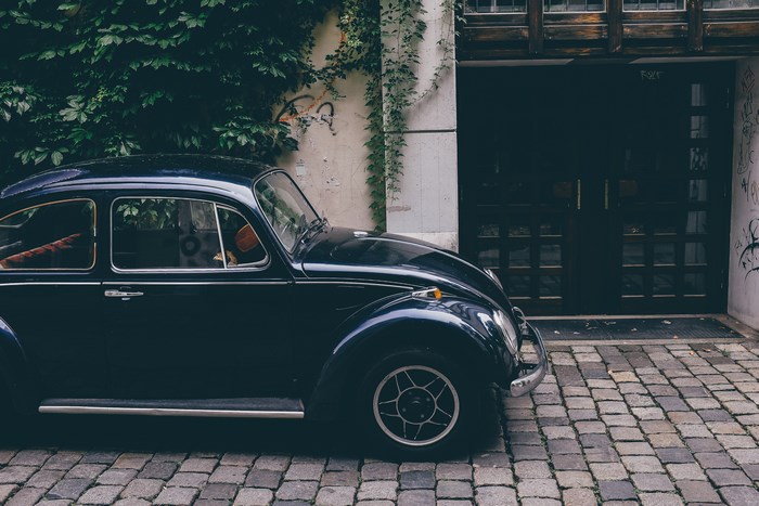 Black Volkswagen Beetle parked on cobblestone street
