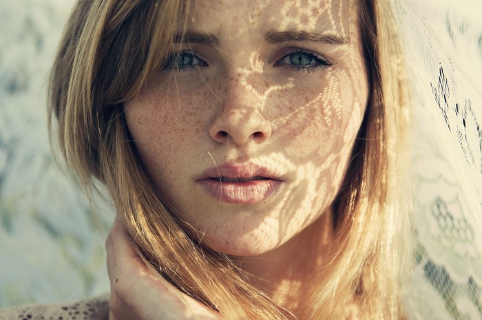 Woman with freckles and lace shadow