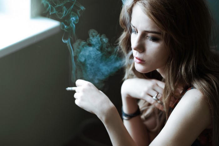 Woman smoking a cigarette with smoke rising