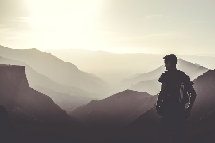 Man with backpack on mountain overlooking misty valley