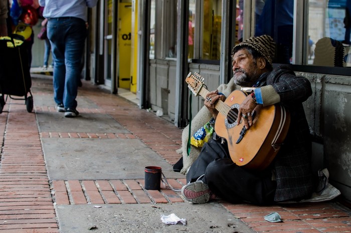 Elderly man playing guitar on a city sidewalk