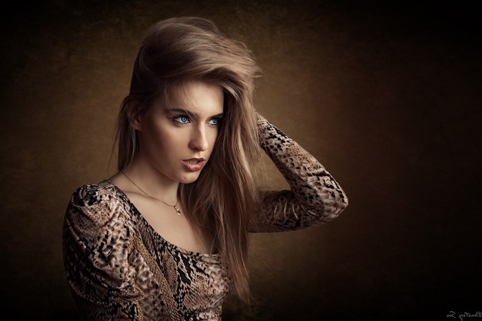Woman with blonde hair and blue eyes wearing a snake print dress