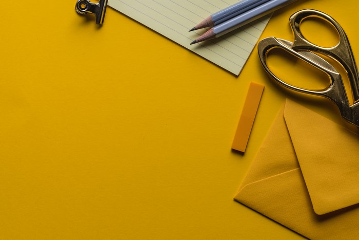 Yellow desk with stationery, scissors, and envelope