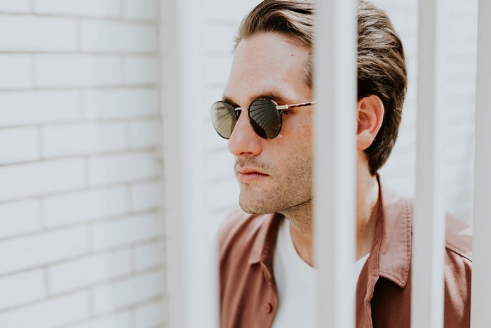 Man wearing sunglasses in front of a brick wall