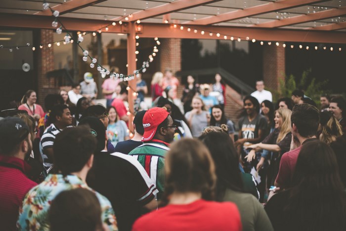 People dancing outdoors under fairy lights at a party
