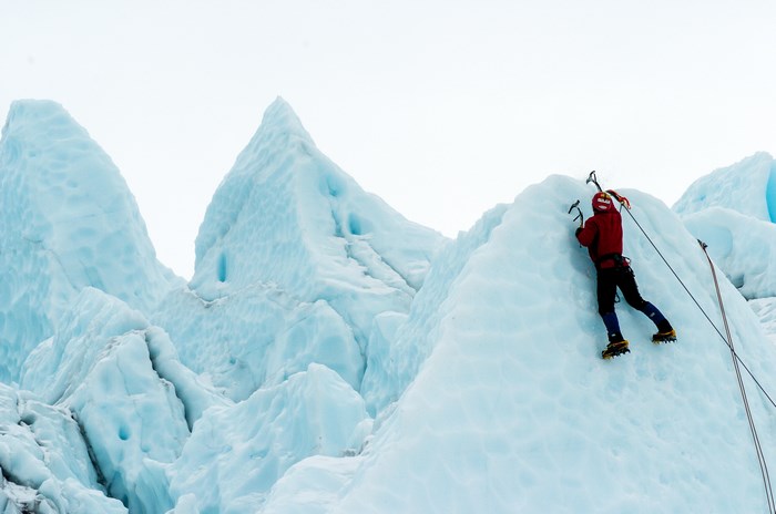 Person ice climbing on a glacier with ice axes