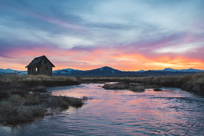 Abandoned cabin by a river at sunset