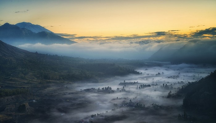 Misty valley with mountains at sunrise