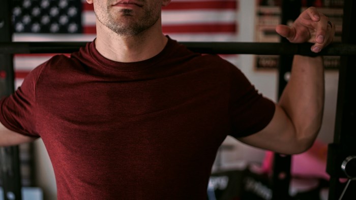Man performing barbell squat in front of American flag