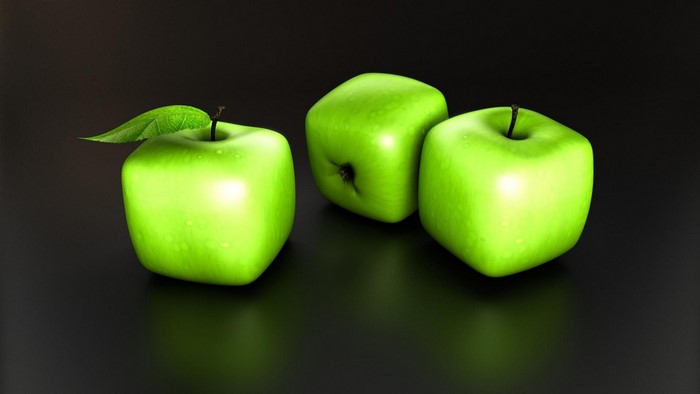 Three green cube apples with a leaf on a dark background