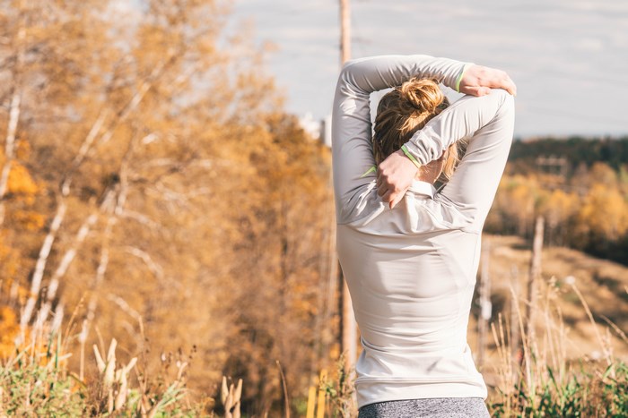 Woman stretching in a forest during fall