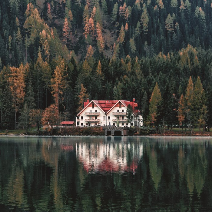 White house with red roof on a lake in autumn forest